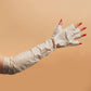 White disposable gloves worn by a person with red nail polish on a beige background
